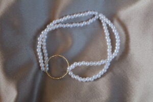 Elastiskt armband med vita pärlor och gulddetalj