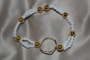 Elastiskt armband med vita pärlor och gulddetaljer
