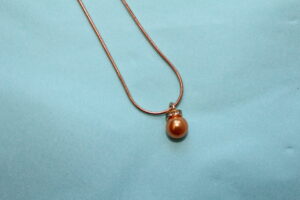 Guldfärgat halsband med orange pärla